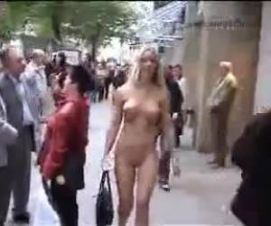 Una descarada rubia exhibicionista se da un paseo completamente desnuda por la calle más concurrida de la ciudad ante la sorprendida mirada de la gente.